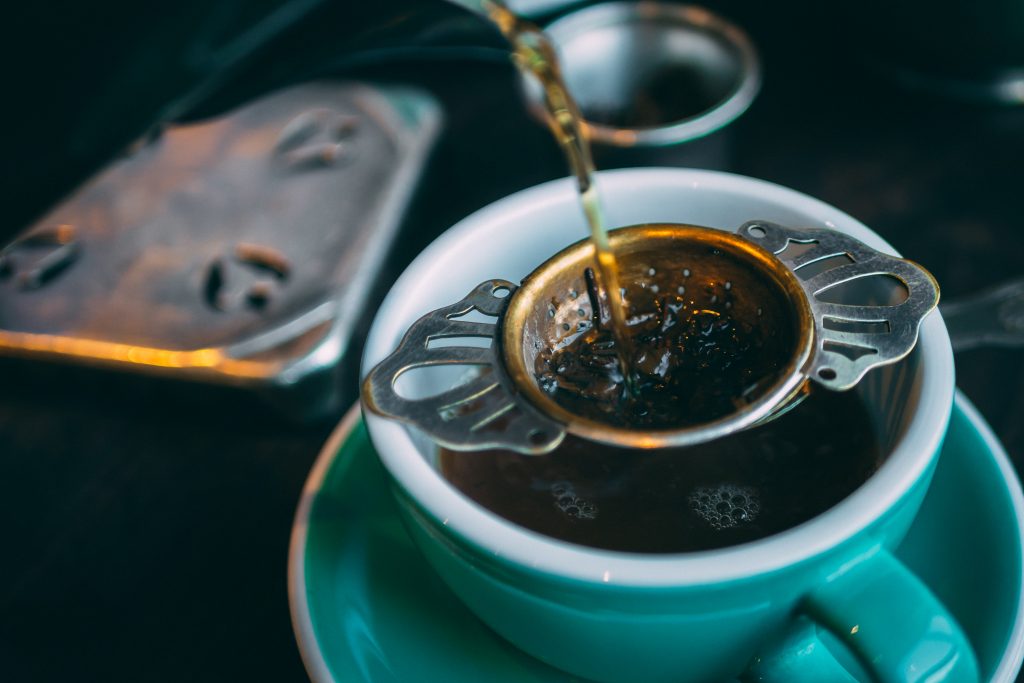 Tea leaves being strained into cup